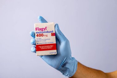 Rio, Brazil - January 27, 2023, hand with protective rubber glove holding medicine box, metronidazole