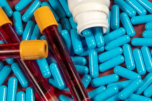 blue medicine capsules and white bottle and blood test tube symbolizing preventive medicine