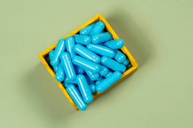 Mavi ilaç kapsülü sarı teslimat kutusunda.