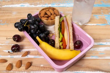 Okulda öğle yemeği sunumu. Üst manzara besleyici gıda, protein, meyve ve tahıllarla dolu çevre dostu beslenme çantalarını gösteriyor.