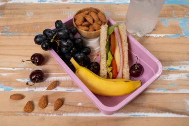 Okulda öğle yemeği sunumu. Üst manzara besleyici gıda, protein, meyve ve tahıllarla dolu çevre dostu beslenme çantalarını gösteriyor.