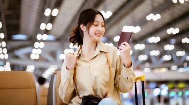 Tatil için havaalanında bekleyen Asyalı kadın. Kameraya bakan Asyalı genç bir kadının portresi. Yüz ifadesi mutlu.