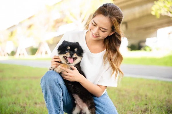 stock image Happy young asian woman playing and sitting on grass in the park with her dog. Pet lover concept