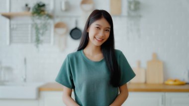 Kameraya bakan Asyalı genç bir kadının portresi. Yüz ifadesi mutlu.