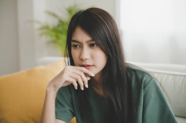 İşle ya da ilişkilerle ilgili sorunlardan bıkmış Asyalı bir kadın kanepeye oturmuş, umutsuzluk ve endişe duyuyor, yalnızlık çekiyor, psikolojik sorunlar yaşıyor.