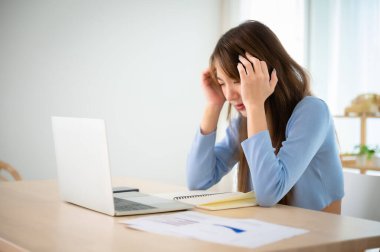 Ofis sendromu. Çok çalışan yorgun Asyalı kadın baş ağrısı çekiyor, bilgisayardan sonra görme sorunu yaşıyor. Evde yorgunluk çeken stresli genç bir kadın.