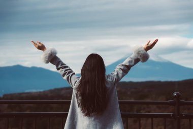 Kış tatili konsepti, genç Asyalı kadın palto giyiyor ve dinleniyor. Yükselir ve kışın dağları seyretmekten zevk alır.