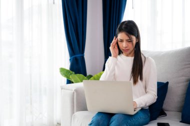 Ofis sendromu. Çok çalışan yorgun Asyalı kadın baş ağrısı çekiyor, bilgisayardan sonra görme sorunu yaşıyor. Evde yorgunluk çeken stresli genç bir kadın.