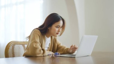 Ev bilgisayarında çalışan gülümseyen Asyalı genç kadın. Genç Asyalı öğrenci bilgisayar eğitimi alıyor, sanal eğitim alıyor, e-öğreniyor, evde online eğitim webinar izliyor.