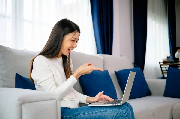 Jonge Aziatische Vrouw Die Thuis Aan Haar Laptop Werkt Grijnzend — Stockfoto