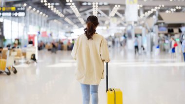 Uluslararası havaalanı terminali. Bavullu ve havaalanında yürüyen Asyalı güzel bir kadın.
