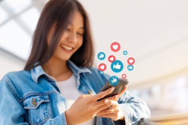 Genç Asyalı kadınlar şehirde canlı yayın videoları izliyorlar. Mutlu kadın eğlence için cep telefonu sosyal medya uygulaması kullanıyor