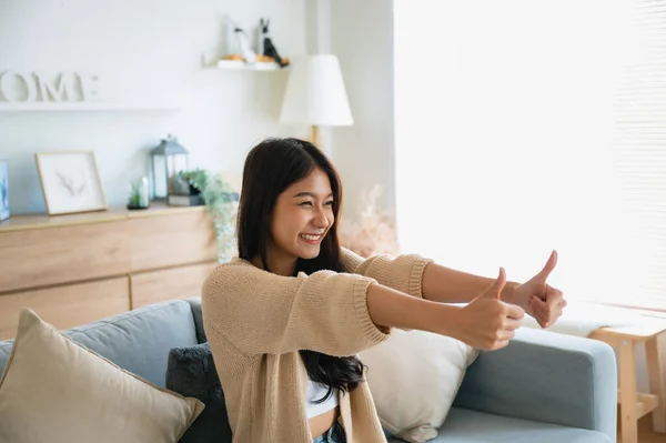 stock image Happy teen asian girl blogger smiling face waving hand talking to webcam recording vlog, social media influencer streaming, making video call at home. She thumb up good or better