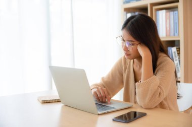 Oturma odasında bilgisayar üzerinde çalışan genç Asyalı kadın duygusal çalkantı, ciddi stres, yalnızlık, endişe ve umutsuzluk yaşıyor.