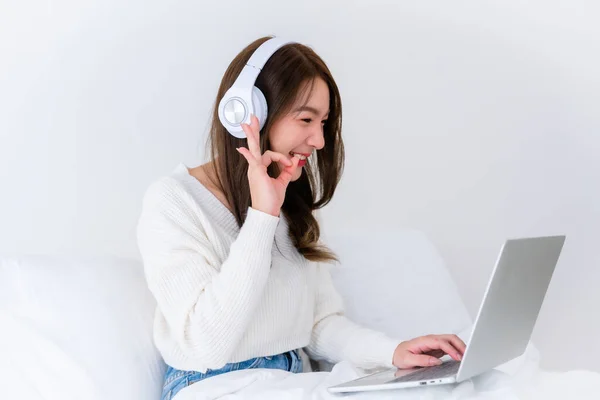 stock image Morning Time in Bedroom Young Asian Woman Happy Working on Computer Laptop, Wearing headset, Sitting on Bed at House