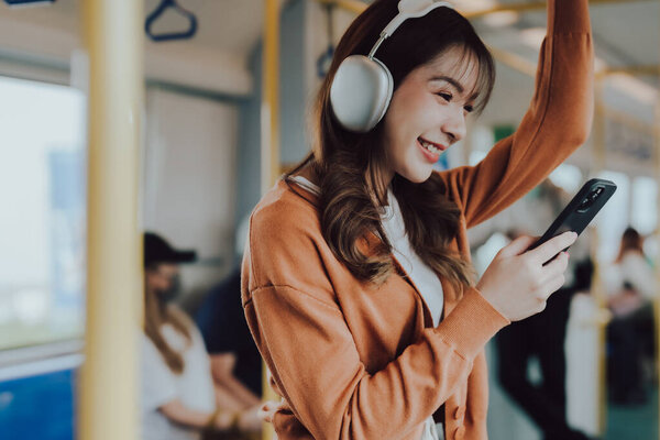 Young Asian Woman Passenger and Listening Music, Using Mobile Smartphone in Subway Sky Train. Lifestyle in City and Daily Urban Life. Transportation Concept