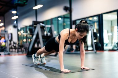 Genç Asyalı kadın fitness merkezinde egzersiz tahtası pozisyonu alıyor. Sağlıklı ve vücut geliştirici kavramı