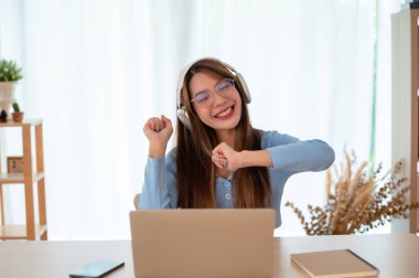 Asyalı bir kadının kazanmasını ya da bilgisayar laptopunda ecommerce alışveriş teklifi almasını kutlayan komik bir coşku. Kazanan mutlu kız, başarıyı kutlayan dizüstü bilgisayara bakıyor.