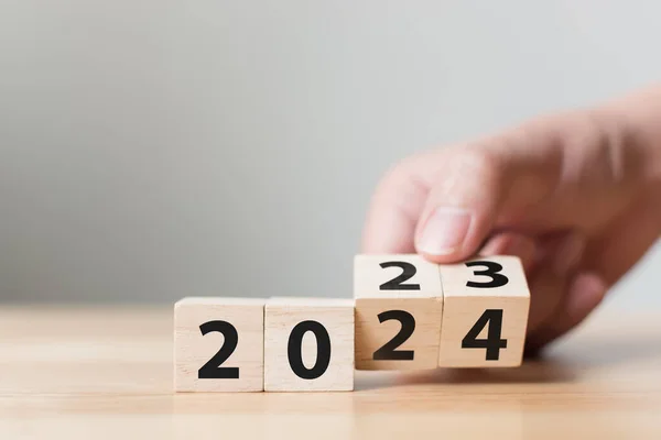 2023年改为2024年 把木制立方体块翻过来 新年决心目标概念 图库图片