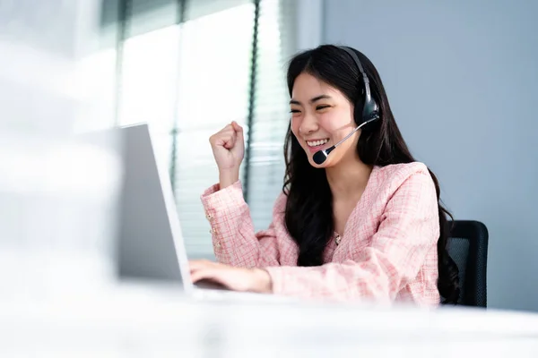 Successful Asian Businesswoman Triumphing Using Laptop. Business Woman Wearing Headphone, Business Advisor, Call Center Worker, Company Representative, Support Service Operator, Online Consultation