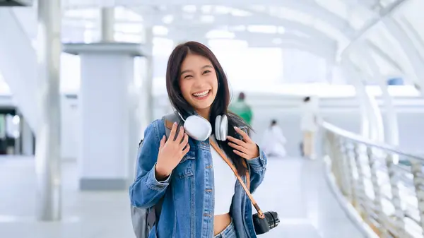 年轻的亚洲女人用耳机听好听的音乐 在城市里散步 女孩快乐 女人的爱听音乐 使她放松并享受生活 免版税图库图片