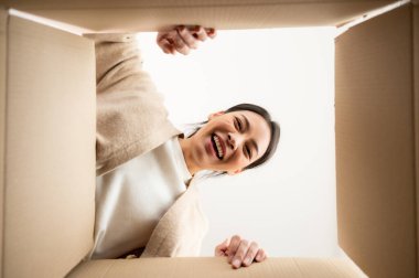 Bavulları boşaltan Asyalı genç bir kadın. Kutuyu açıp içine bakmak. Paket kutusu, teslimat servisi. İnsan duyguları ve yüz ifadesi