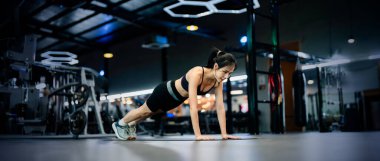 Genç Asyalı kadın fitness merkezinde egzersiz tahtası pozisyonu alıyor. Sağlıklı ve vücut geliştirici kavramı