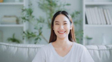 Gülümseyen ve kameraya bakan Asyalı genç bir kadının ön görüntüsü. Mutlu yüz ifadeleri ve olumlu duygular