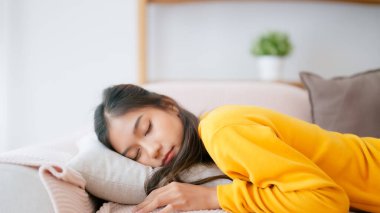 Asyalı kadın koltukta dinleniyor, işten sonra bitkin hissediyor, enerjisi yok, ya da çok çalışıyor, çok yorgun ve motivasyonsuz.