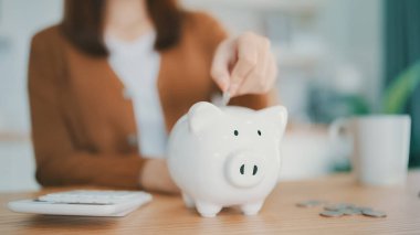 Genç Asyalı kadın kumbaraya para koyuyor. Para ve mali yatırım tasarrufu