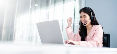 Başarılı Asyalı İş Kadını Dizüstü bilgisayar kullanarak Zafer kazandı. İş Kadınları Kulaklık, İş Danışmanı, Çağrı Merkezi İşçisi, Şirket Temsilcisi, Destek Hizmeti Operatörü, Çevrimiçi Danışmanlık