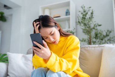 Cihaz ekranında kötü haber var. İşle ya da ilişkilerle ilgili sorunlardan bıkmış Asyalı bir kadın kanepeye oturmuş, umutsuzluk ve endişe duyuyor, yalnızlık çekiyor, psikolojik sorunlar yaşıyor.