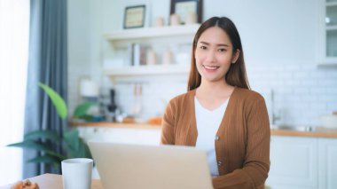 Kameraya bakan Asyalı genç bir kadının portresi. Yüz ifadesi mutlu.