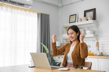 Asyalı bir kadının kazanmasını ya da bilgisayar laptopunda ecommerce alışveriş teklifi almasını kutlayan komik bir coşku. Heyecanlı mutlu kız kazanan başarıyı kutlayan deftere bakıyor.