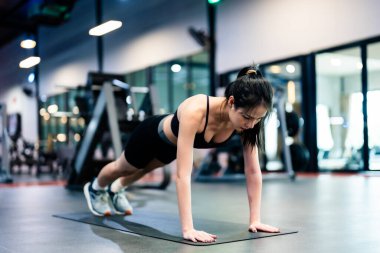 Genç Asyalı kadın fitness merkezinde egzersiz tahtası pozisyonu alıyor. Sağlıklı ve vücut geliştirici kavramı