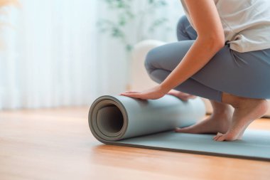Genç Asyalı kadın yoga yapıyor, evdeki oturma odasında paspasın üstünde kıvrılıyor.