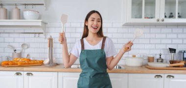 Genç Asyalı kadın mutfakta dans ediyor. Güzel bir kadının hafta sonu boş zamanlarında evde dinlenmesinin keyfi.