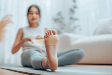 Genç Asyalı kadın pilates egzersizi yapıyor. Kapalı alandaki yoga minderinde omuz çalışması için elastik kayışı kullanarak kollarını çekiyor. Evde direniş bandı egzersizi