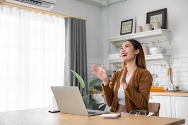 Asyalı bir kadının kazanmasını ya da bilgisayar laptopunda ecommerce alışveriş teklifi almasını kutlayan komik bir coşku. Heyecanlı mutlu kız kazanan başarıyı kutlayan deftere bakıyor.