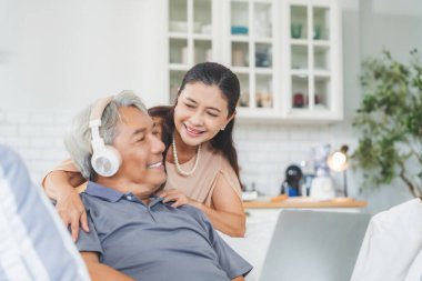 Üst düzey eşler evdeki kanepede birlikte otururken dizüstü bilgisayar kullanıyorlar. Yaşlı çift, kanepede mutlu bir evlilik, destek ve huzurevi sohbeti ile sevgi ve kucaklaşma.