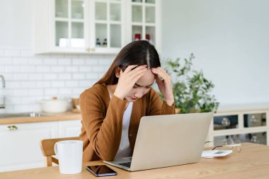 Ofis sendromu. Çok çalışan yorgun Asyalı kadın baş ağrısı çekiyor, bilgisayardan sonra görme sorunu yaşıyor. Evde yorgunluk çeken stresli genç bir kadın.