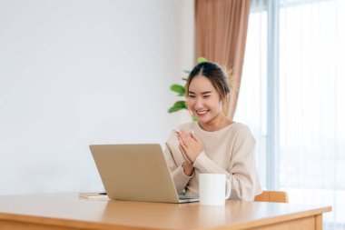 Asyalı bir kadının kazanmasını ya da bilgisayar laptopunda ecommerce alışveriş teklifi almasını kutlayan komik bir coşku. Heyecanlı mutlu kız kazanan başarıyı kutlayan deftere bakıyor.