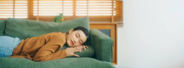 Asyalı kadın koltukta dinleniyor, işten sonra bitkin hissediyor, enerjisi yok, ya da çok çalışıyor, çok yorgun ve motivasyonsuz.