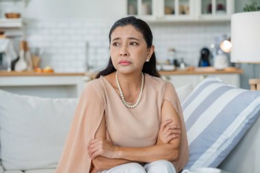 Kanepede oturan üzgün Asyalı son sınıf öğrencisi, düşüncelere dalmış, yalnız, hayal kırıklığına uğramış, evde yalnız, mutsuz, endişeli, kayıp ya da üzgün. Akıl sağlığı sorunları yaşayan yaşlı bir kadın.