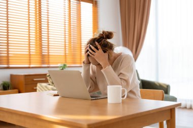 Ofis sendromu. Çok çalışan yorgun Asyalı kadın baş ağrısı çekiyor, bilgisayardan sonra görme sorunu yaşıyor. Evde yorgunluk çeken stresli genç bir kadın.