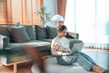Genç Asyalı güzel bir kadın rahat koltukta dinleniyor, evinde dizüstü bilgisayar kullanıyor, sosyal ağda arkadaşlarıyla sohbet eden mutlu bir kız, haftasonunu, film izleyerek, online alışveriş yaparak geçiriyor.