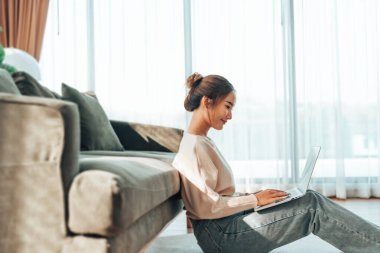 Genç Asyalı güzel bir kadın rahat koltukta dinleniyor, evinde dizüstü bilgisayar kullanıyor, sosyal ağda arkadaşlarıyla sohbet eden mutlu bir kız, haftasonunu, film izleyerek, online alışveriş yaparak geçiriyor.