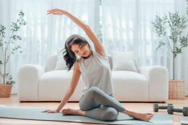 Mutlu genç Asyalı kadın yoga ve omuz egzersizi yapıyor. Oturma odasında yerde oturuyor.