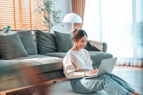 Молодая азиатская красивая женщина отдыхает на удобном диване, используя ноутбук дома, счастливая девушка болтает с друзьями в социальной сети, проводить выходные, смотреть кино, покупки онлайн