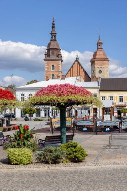 Nowy Sacz, Poland - August 30, 2022: View of the Market Square on a sunny day with decorative colorful flower arrangements. In the background the towers of the Collegiate Basilica of St. Malgorzata